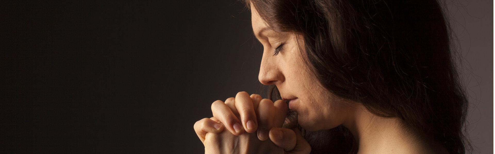 Praying woman on dark background